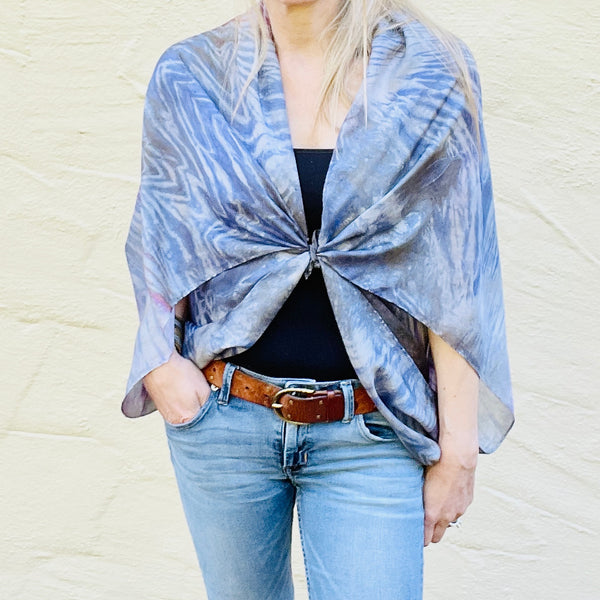 Model is wearing a rainbow multi colored large luxury silk square scarf in striped safari shibori pattern as a jacket tied in front, sustainable wear with many style looks. Best fashion accessory for any season or occasion. Makes a great gift. Handmade one of a kind artisan accessories. Square shaped 43 inches by 43 inches.