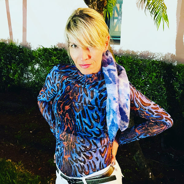Model is wearing an indigo blue luxury silk bandana scarf in animal ikat shibori pattern, sustainable wear with many style looks. Best fashion accessory for any season or occasion. Makes a great gift. Handmade one of a kind artisan accessories. Square shaped 28 inches by 28 inches.