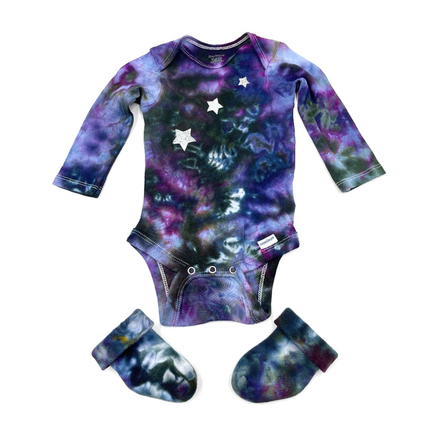 Multi-colored hand dyed baby onesie with star pattern and matching booties on a white background. Gender neutral.