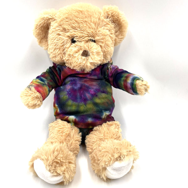 Beige teddy bear wearing multi-colored rainbow spiral swirl hand dyed baby onesie a on a white background. Gender neutral.  Makes a great gift!