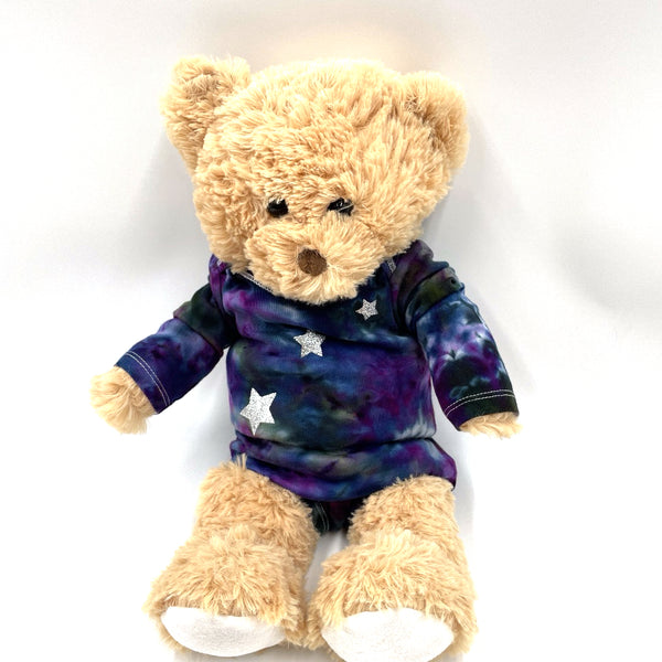 Teddy bear model wearing a multi-colored hand dyed baby onesie with star pattern and matching booties on a white background. Gender neutral.