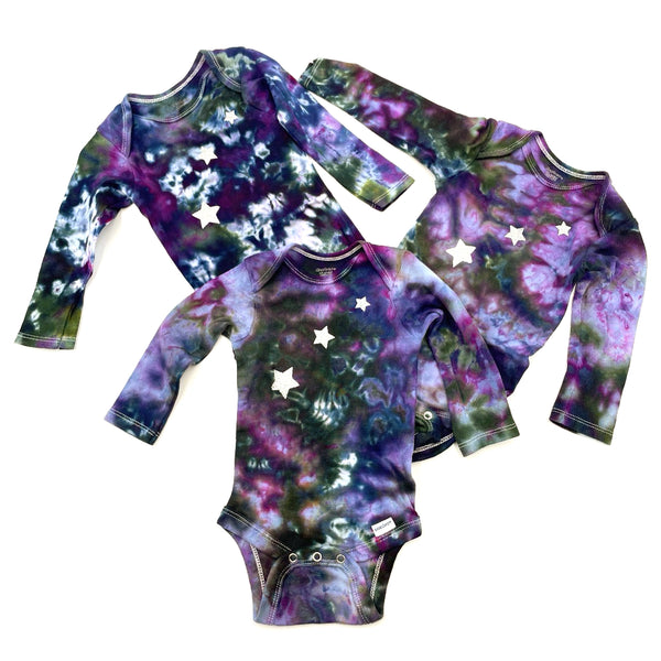 Picture of multi-colored hand dyed baby onesies with star pattern on a white background. Gender neutral.