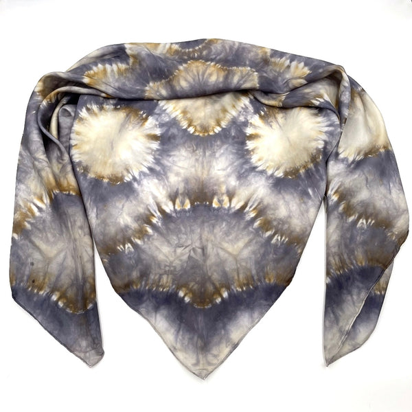 Handmade Tie-dye shibori patterned scarf shawl in shades of gray and beige on a white background.