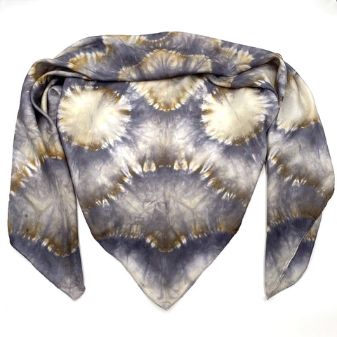 Handmade Tie-dye shibori patterned scarf shawl with kaleidoscope mandala design in shades of gray and beige on a white background.