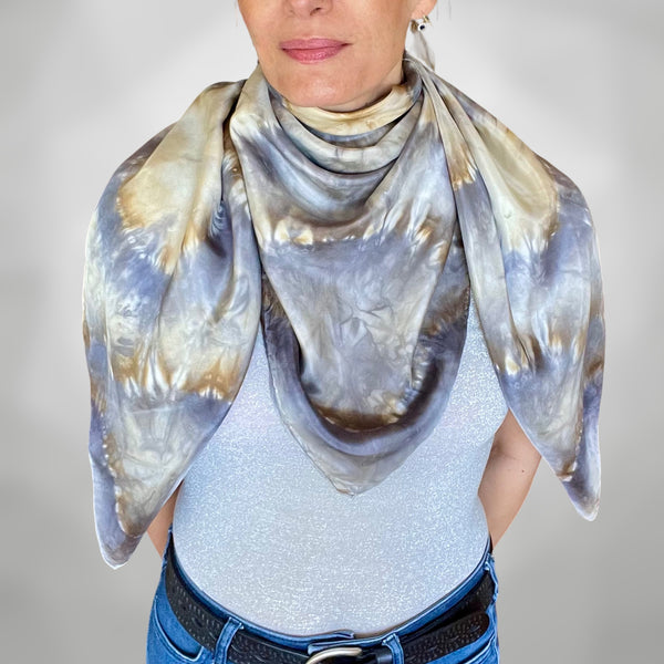 Model wearing a handmade Tie-dye shibori patterned silk scarf around neck with kaleidoscope mandala design in shades of gray and beige on a white background.