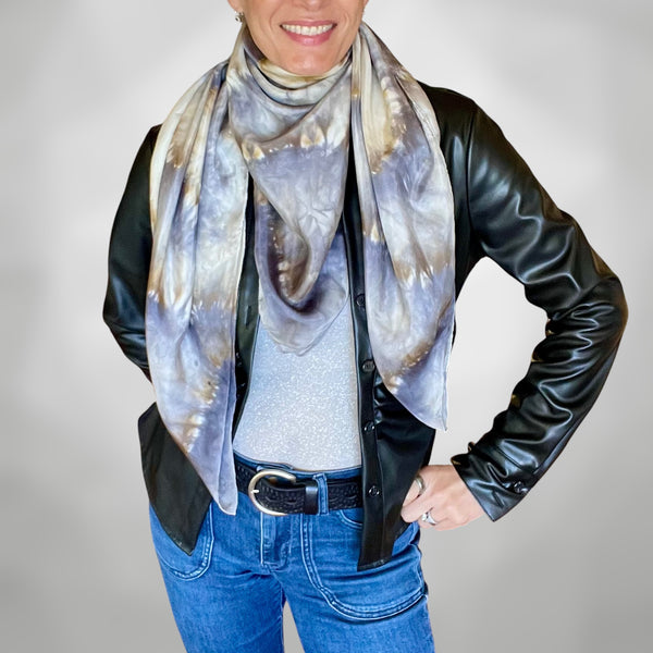 Model wearing a handmade Tie-dye shibori patterned silk scarf around neck with kaleidoscope mandala design in shades of gray and beige on a white background.