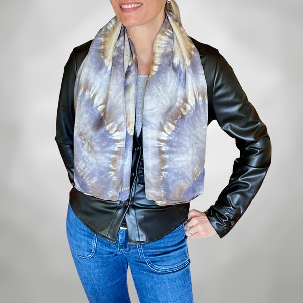 Model wearing a handmade Tie-dye shibori patterned silk scarf around neck with kaleidoscope mandala design in shades of gray and beige on a white background.