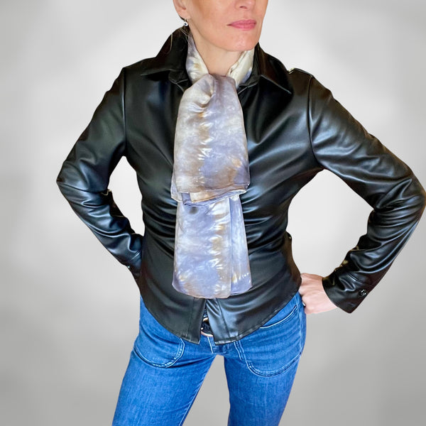 Model wearing a handmade Tie-dye shibori patterned silk scarf around neck with kaleidoscope mandala design in shades of gray and beige on a white background.