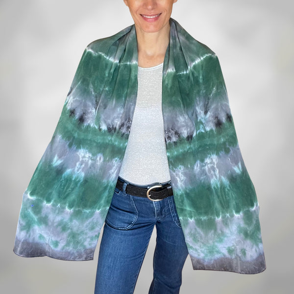 Person wearing a green and gray tie-dye scarf on a plain background
