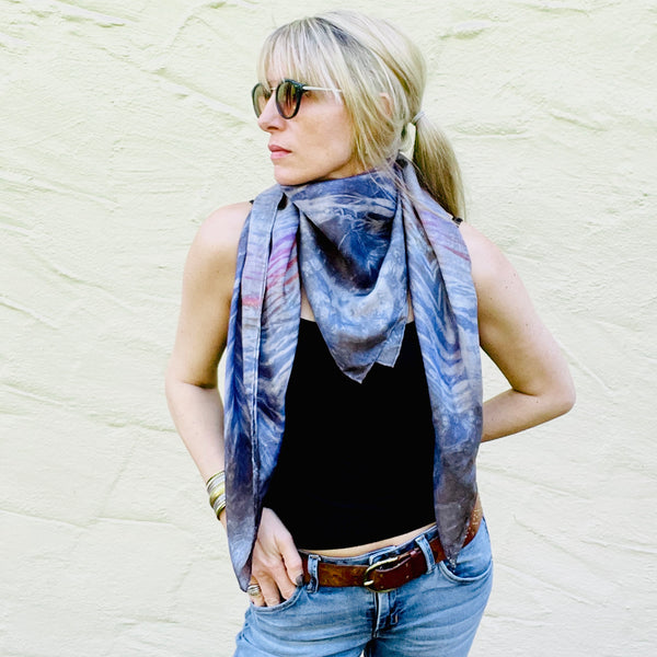 Model is wearing a rainbow multi colored large luxury silk square scarf in striped safari shibori pattern around neck, sustainable wear with many style looks. Best fashion accessory for any season or occasion. Makes a great gift. Handmade one of a kind artisan accessories. Square shaped 43 inches by 43 inches.