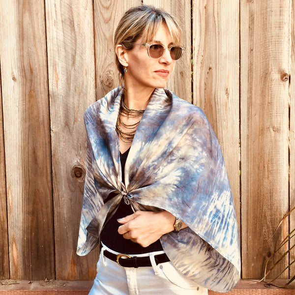Model is wearing a slate grey, blue and white luxury silk scarf shawl in tie dye shibori pattern, sustainable wear with many style looks. Best fashion accessory for any season or occasion. Makes a great gift. Handmade one of a kind artisan accessories. Square shaped 43 inches by 43 inches.