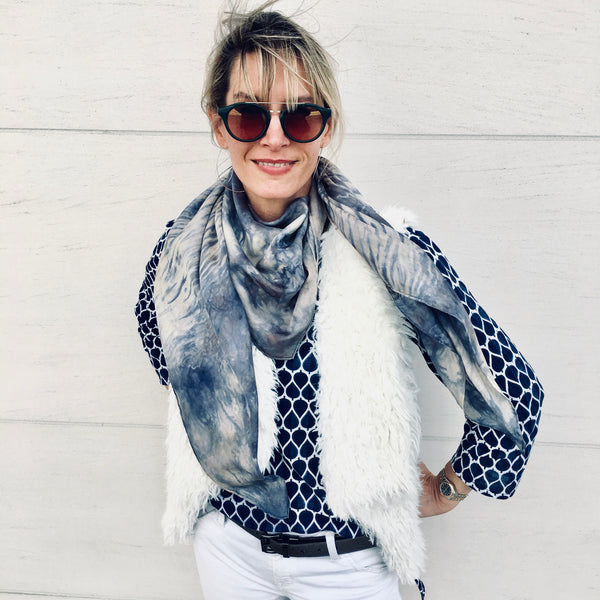 Model is wearing slate grey, blue and white luxury silk scarf shawl in tie dye shibori pattern, sustainable wear with many style looks. Best fashion accessory for any season or occasion. Makes a great gift. Handmade one of a kind artisan accessories. Square shaped 43 inches by 43 inches.